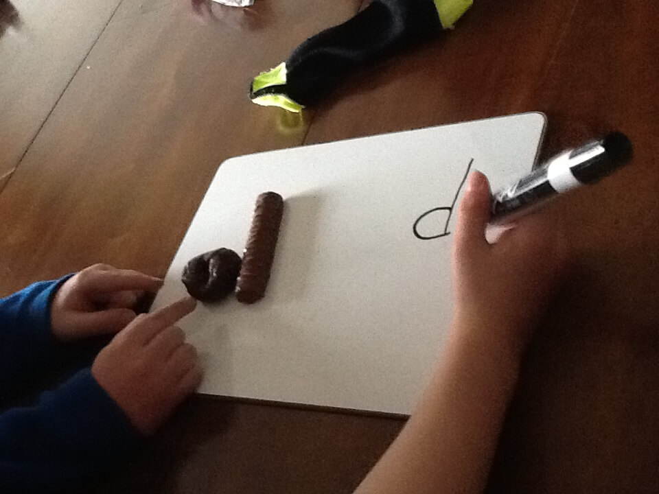 Student writing the letter d on a whiteboard